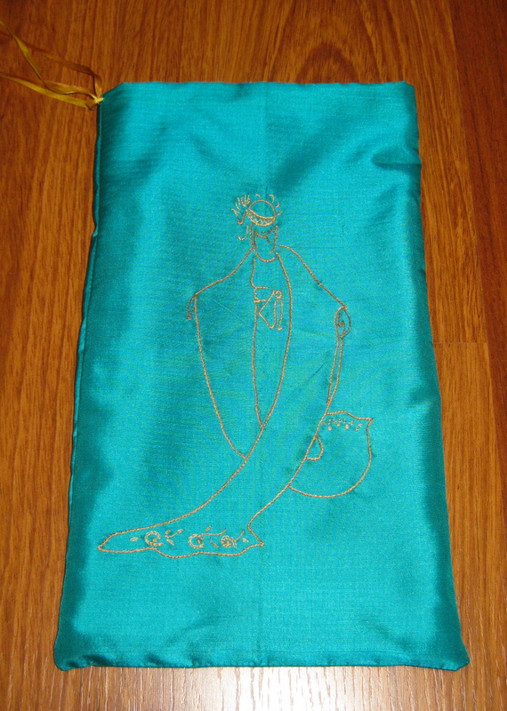 A green silk pouch embroidered with the image of a woman in a long yellow robe