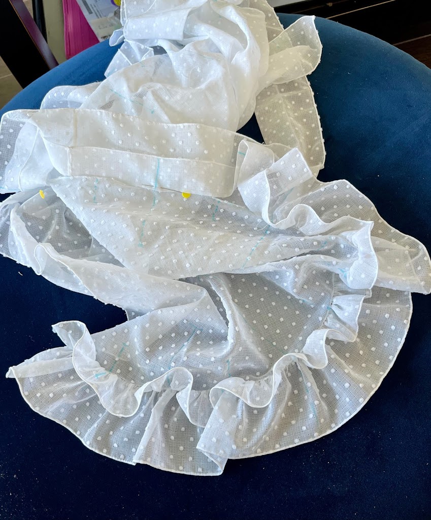 A ruffle is half-sewn onto a white cotton fichu.