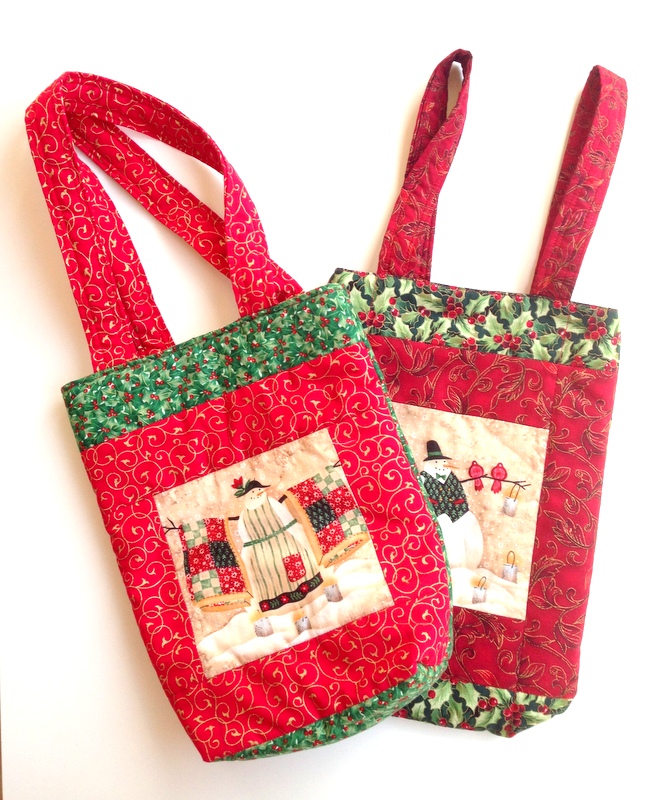 two christmas tote bags made of scraps of christmas quilting fabric.