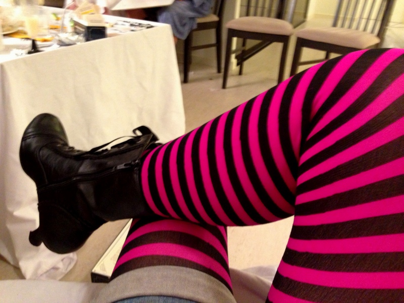 A pair of crossed legs, wearing pink striped stockings and black lace-up boots.  It is 2:30 in the morning and time for bed.