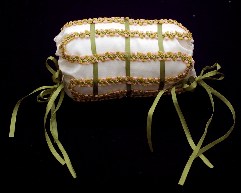 An American Girll doll muff cover in white silk with a trellis design in green silk ribbons and french ribbon braid