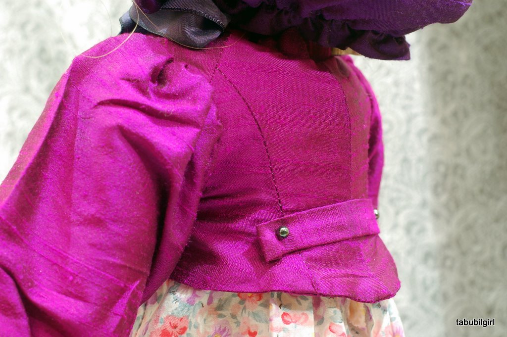 Close up view of an American Girl doll wearing a historically inspired regency spencer with a flared peplum