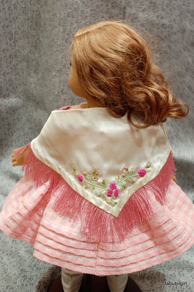 An American Girl doll wears a fringed silk shawl embroidered with pink ribbon roses