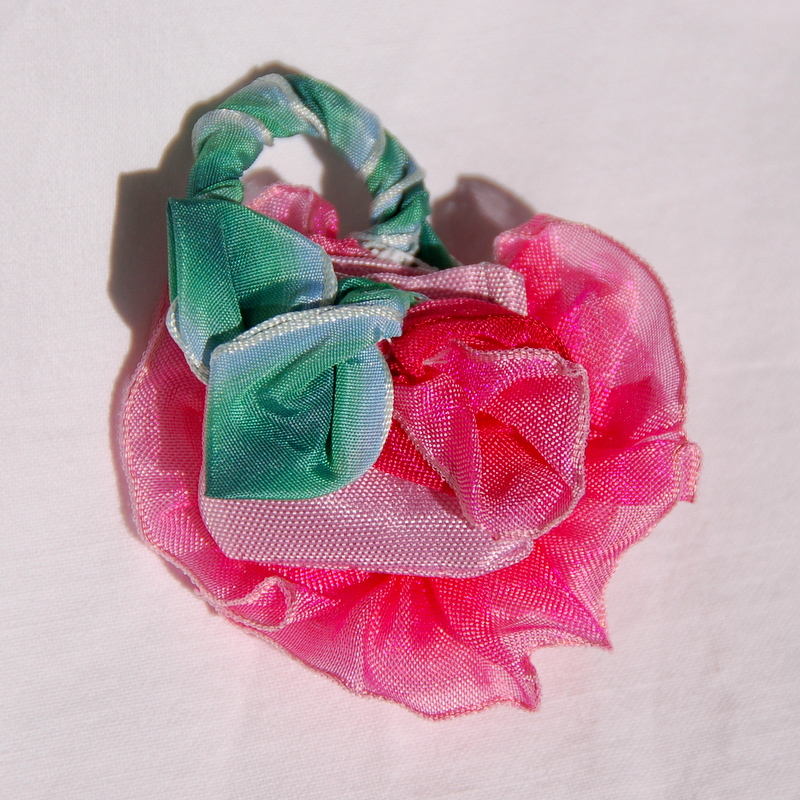 The back side of a doll size purse made from a pink wired ribbon flower.