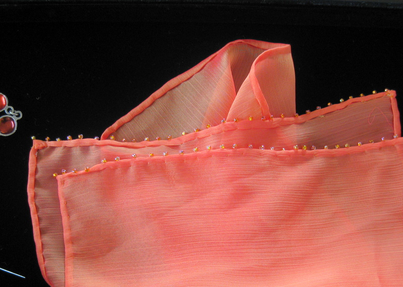 Close-up of the beaded edges of an orange chiffon shawl