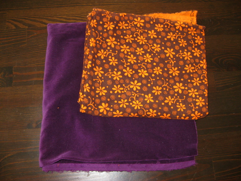Orange cotton velvetten fabric is sitting on purple velveteen fabric.  They are both covered in lint