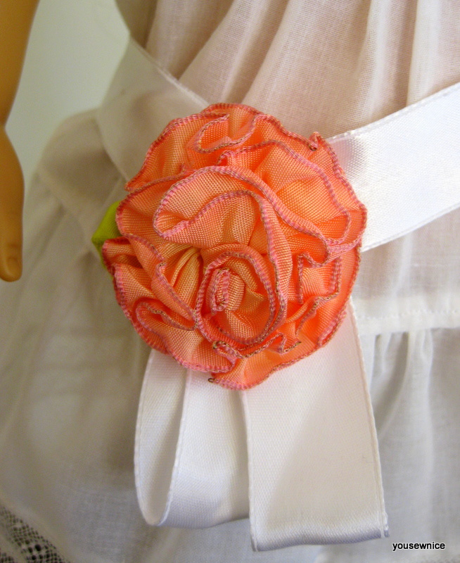 Close up of a wired ribbon flower holding shut a doll sash