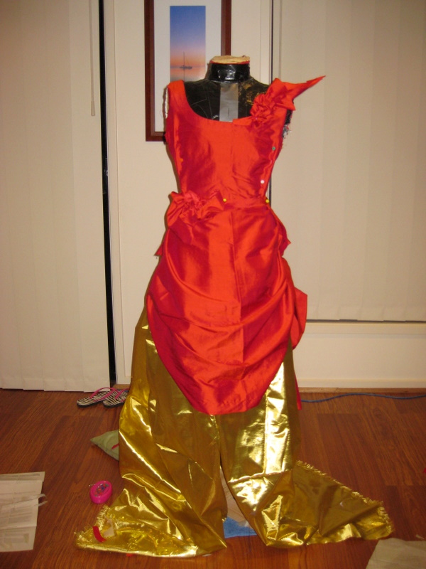 Red and gold fabric is draped over a mannequin. front view.