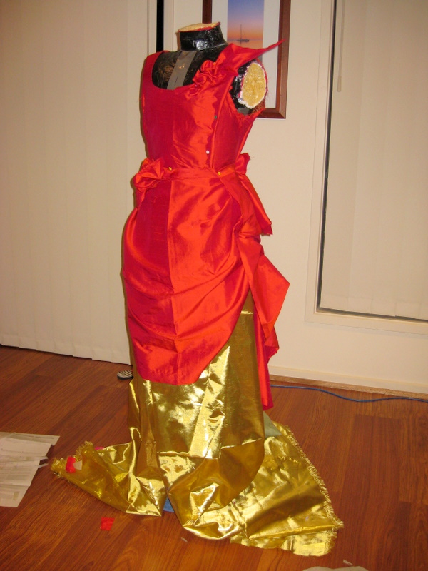 Side view of Red and gold fabric draped over a mannequin.