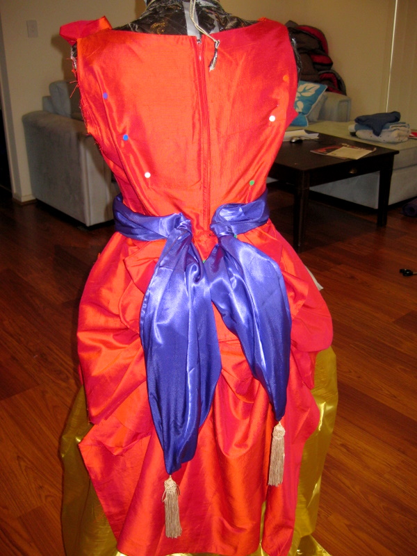 a purple sash pinned to the back of a red silk ballgown