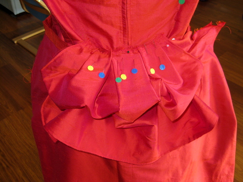 detail of a red silk peplum pinned to a bodice