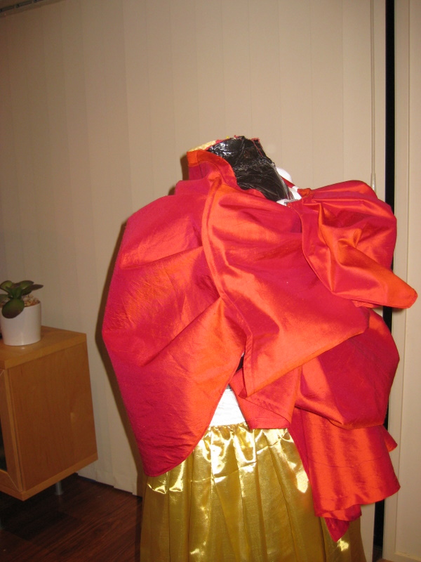 A red silk bustle skirt is mounted on a mannequin
