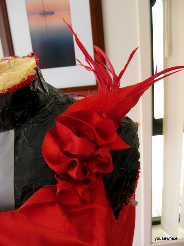 detail of a fire red silk and feather shoulder corsage.