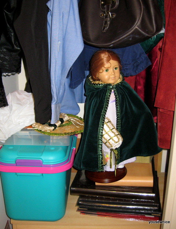 An American Girl Doll dressed in a regency costume is hiding in a closet