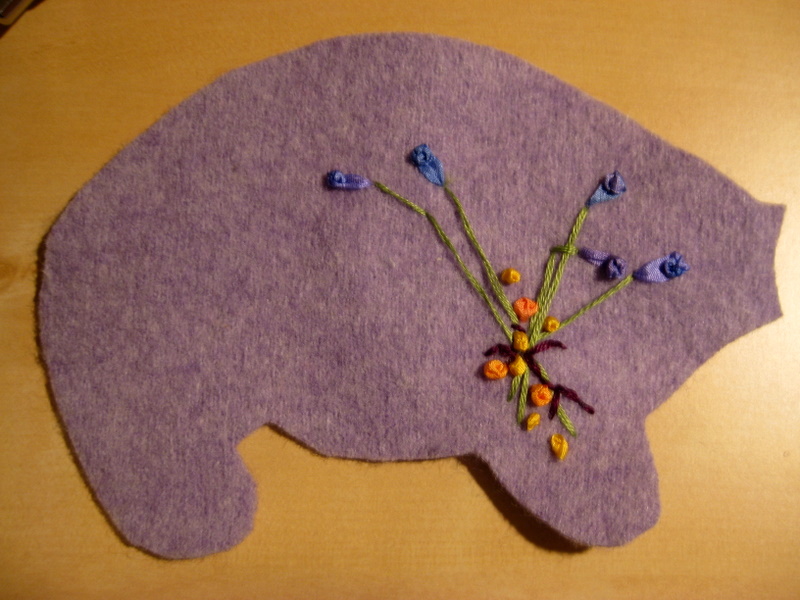 the side panel of an embroidered wool pig lies on a table