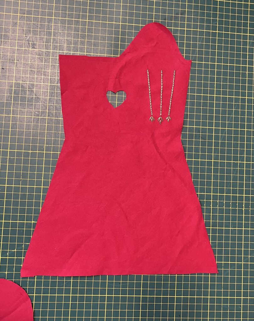 A cut-out of a red cotton mitt lies on a green cutting board.