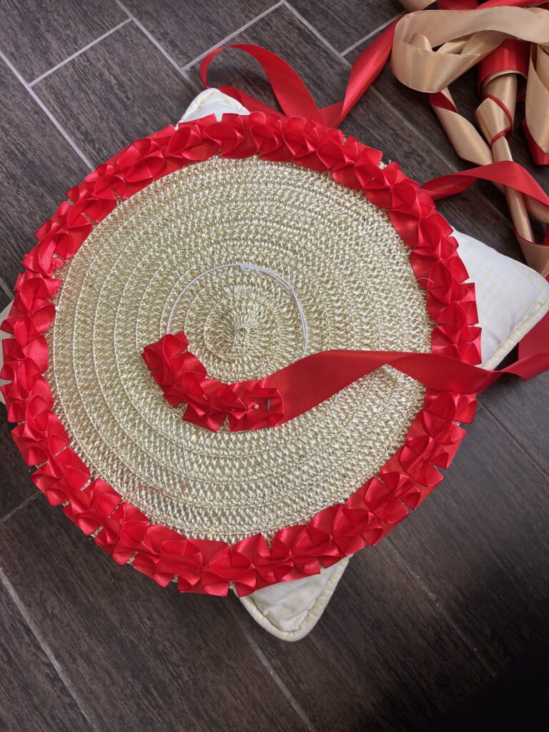 A gold placemat is being decorated with two rows of box pleated red thread - one along the edge and one in a circle around the center