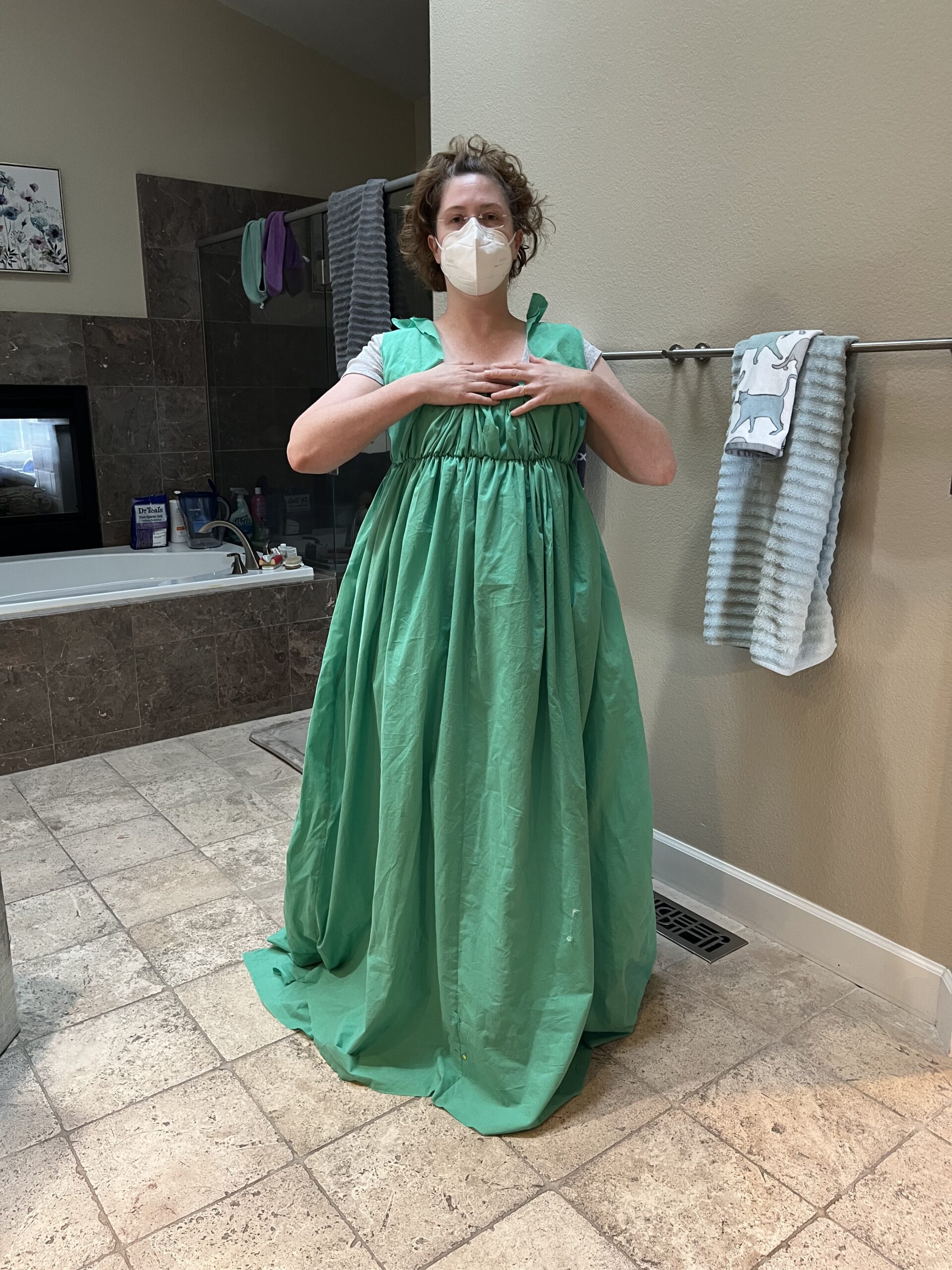 Tabubilgirl wears a bulky green belted round gown. Her hands are crossed across her chest.