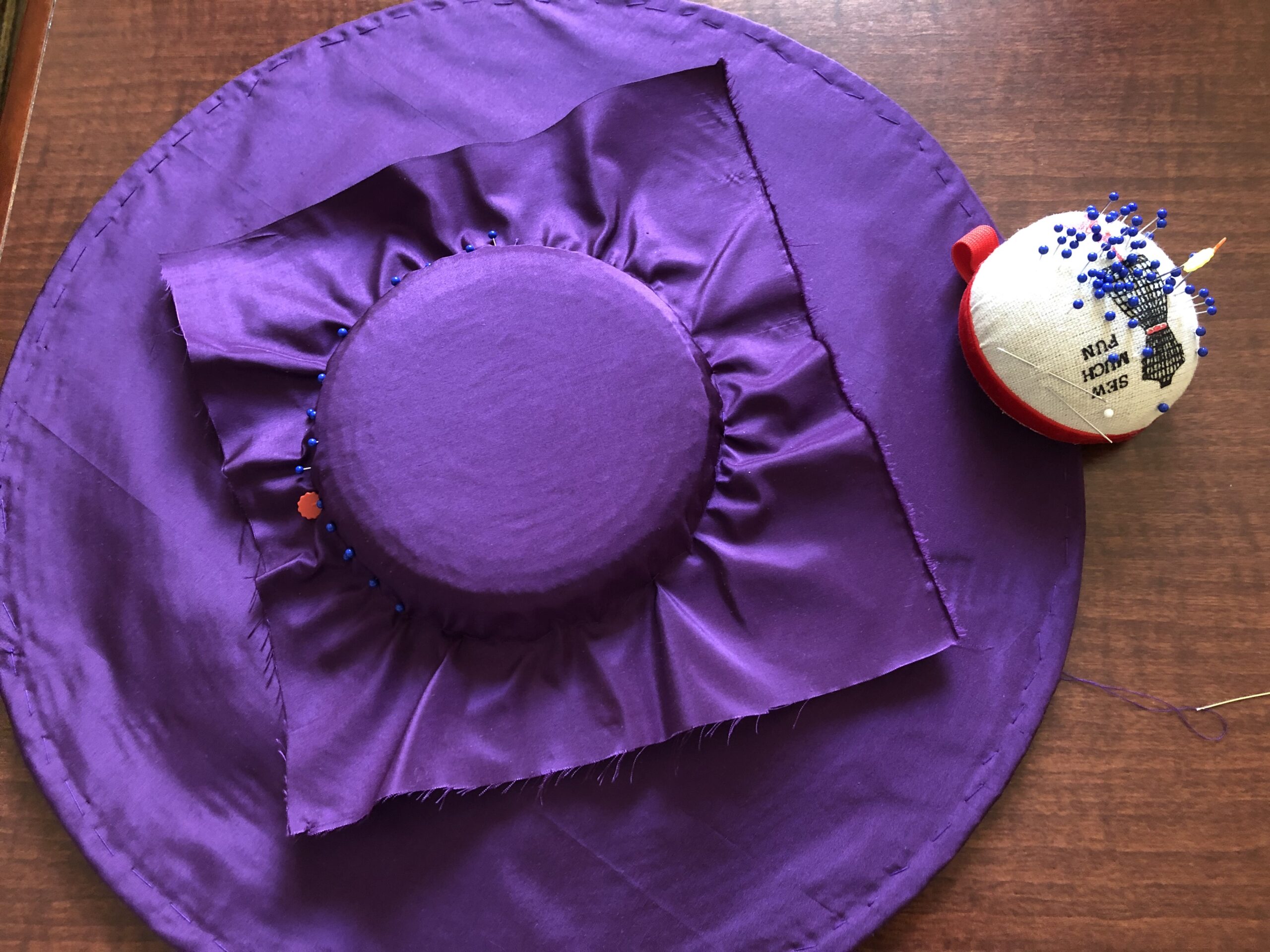 A bergere hat in the process of being covered with purple silk taffeta.