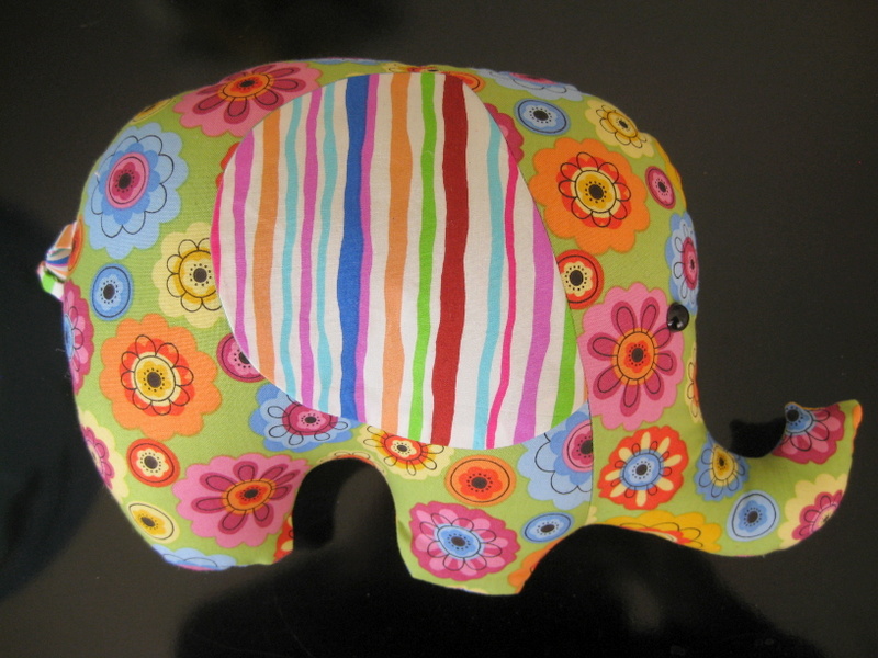 A stuffed elephant made of psychedelic floral fabric with rainbow striped ears.
