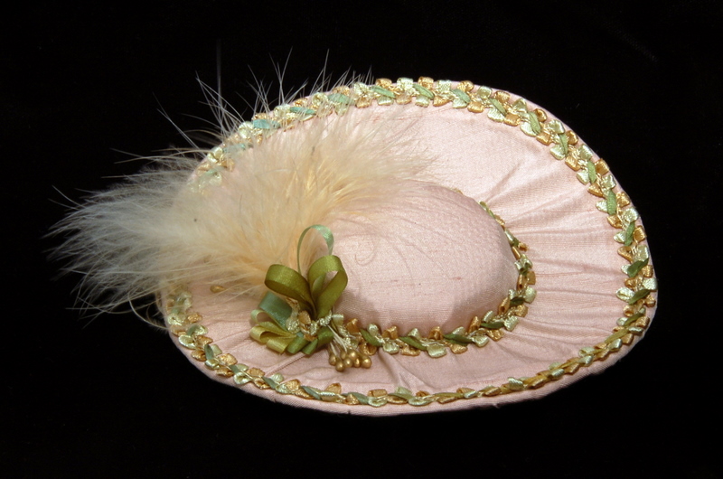 a small peach colored doll hat with a fluffy feather trim