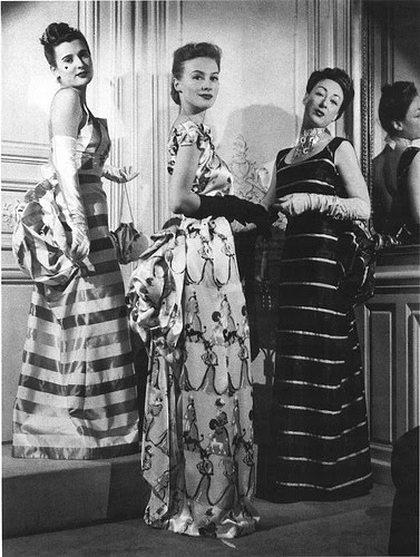 Three women wearing schiaparelli dresses look at the camera