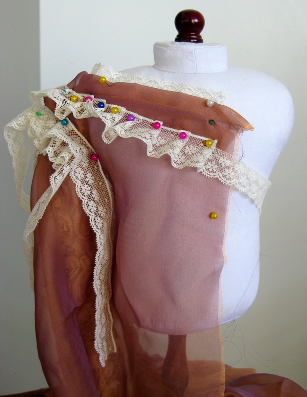 lace and chiffon are draped on a doll mannequin to create a bertha