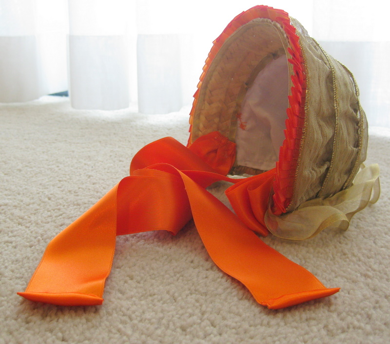 An American Girl Doll 1860s bonnet with bright orange ribbon ties