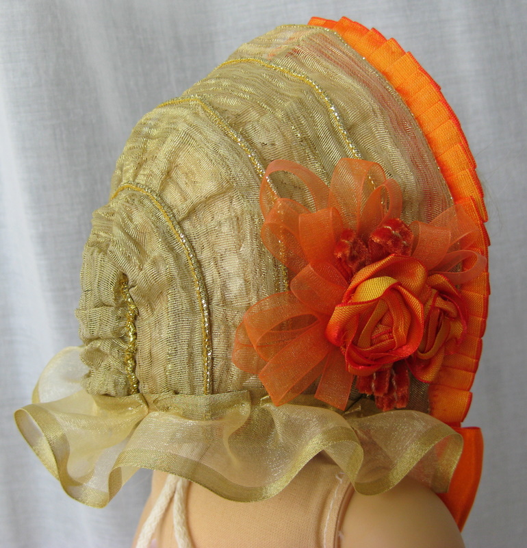 Rear view of an 1860s bonnet for an American Girl doll. The bonnet is trimmed with gold and orange ribbons.