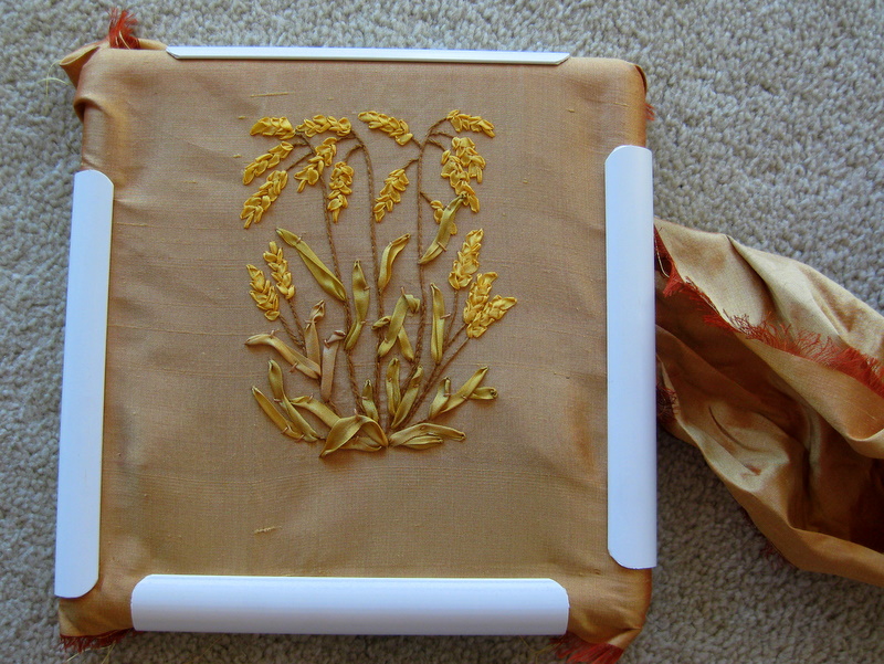 A panel of ribbon embroidered wheat on gold silk dupioni sits in an embroidery frame