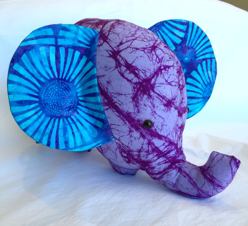 An elephant made of purple batik fabric with blue batik ears.