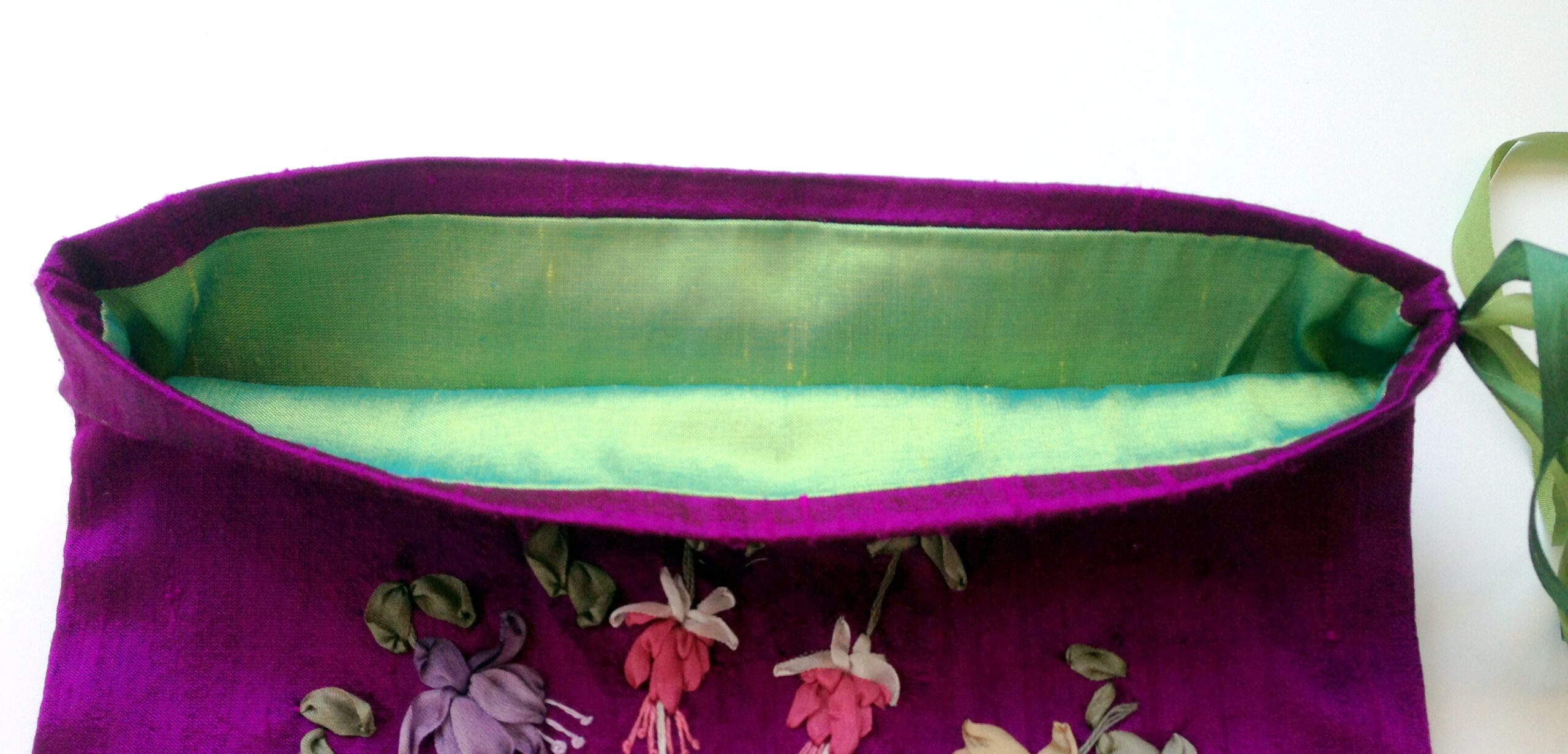 The opening of a purple silk jewellery pouch - the lining is bright green