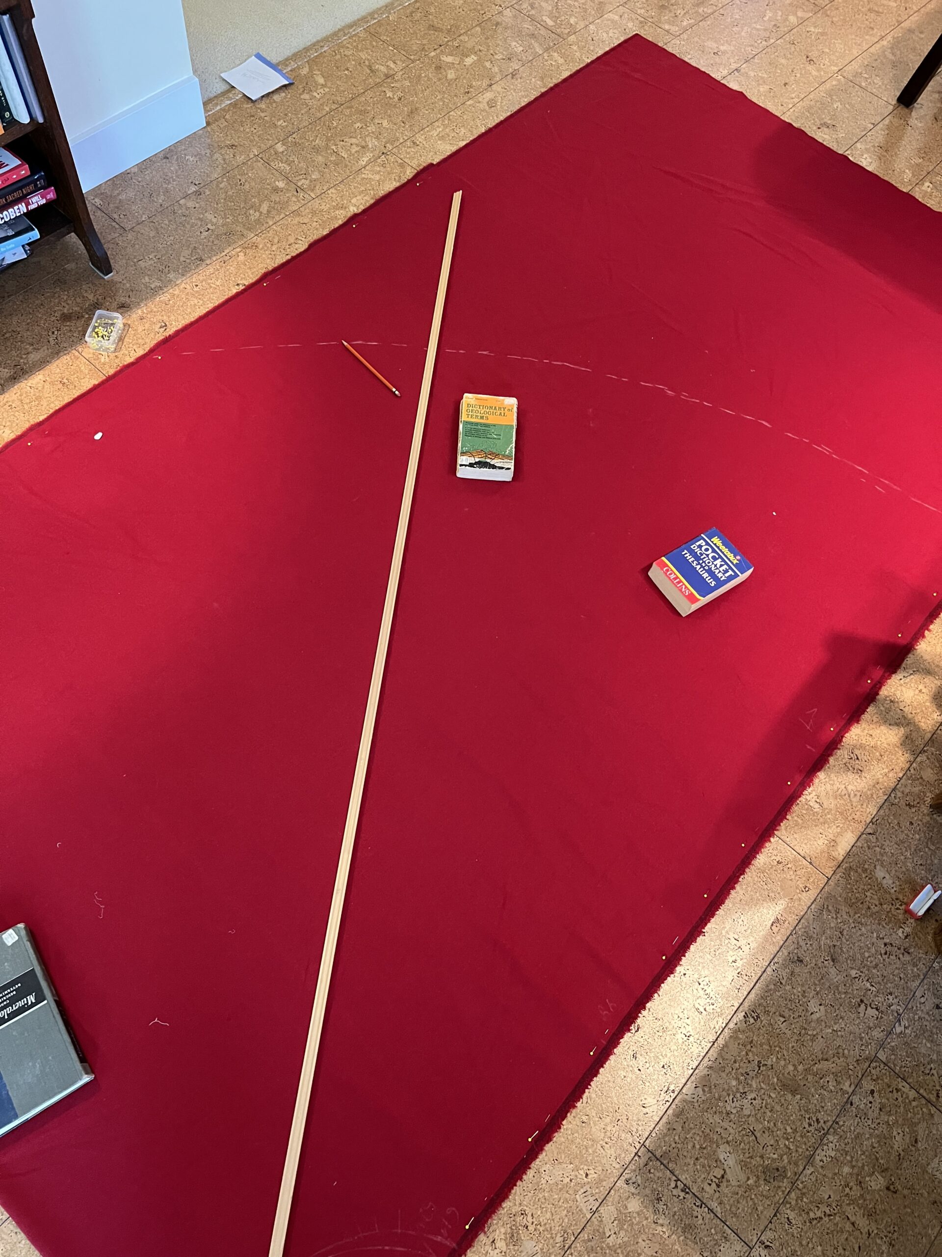 A long stick traces out a curve on a length of red wool