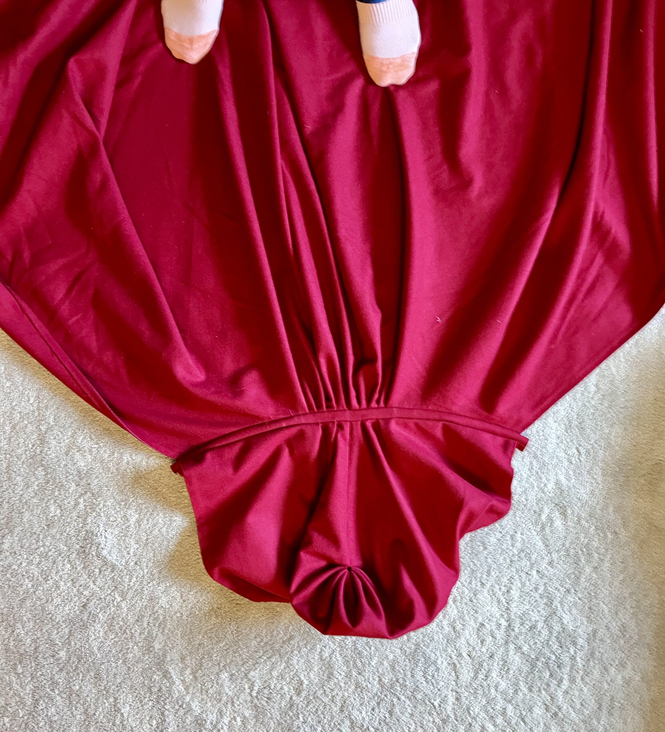 A red Pacific Northwestern 1790s Cardinal Cloak lies on a carpet