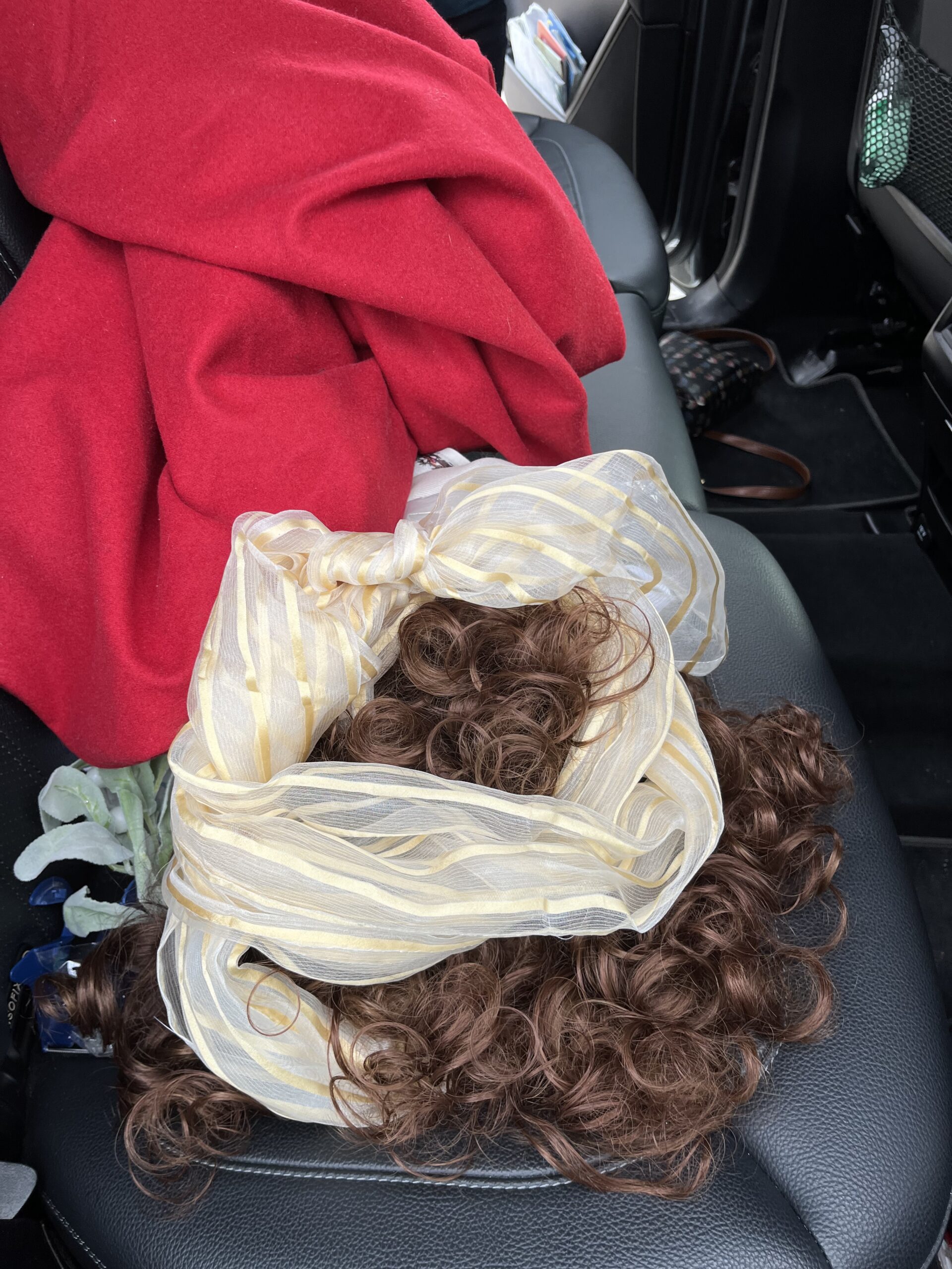 A wig wrapped in an 18th Century chiffonet sits on a car seat in the aftermath of being caught in a stiff wind