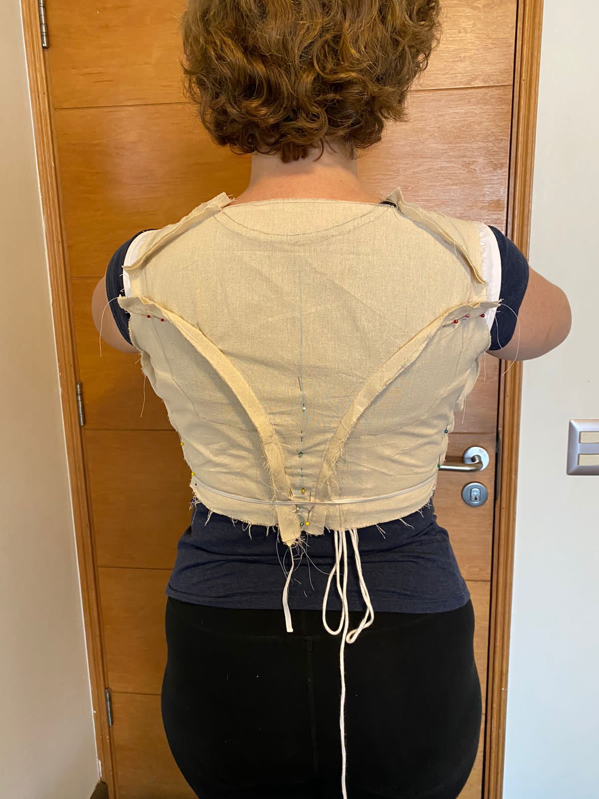 back view of tabubilgirl being fitted for a new 1790s round gown bodice