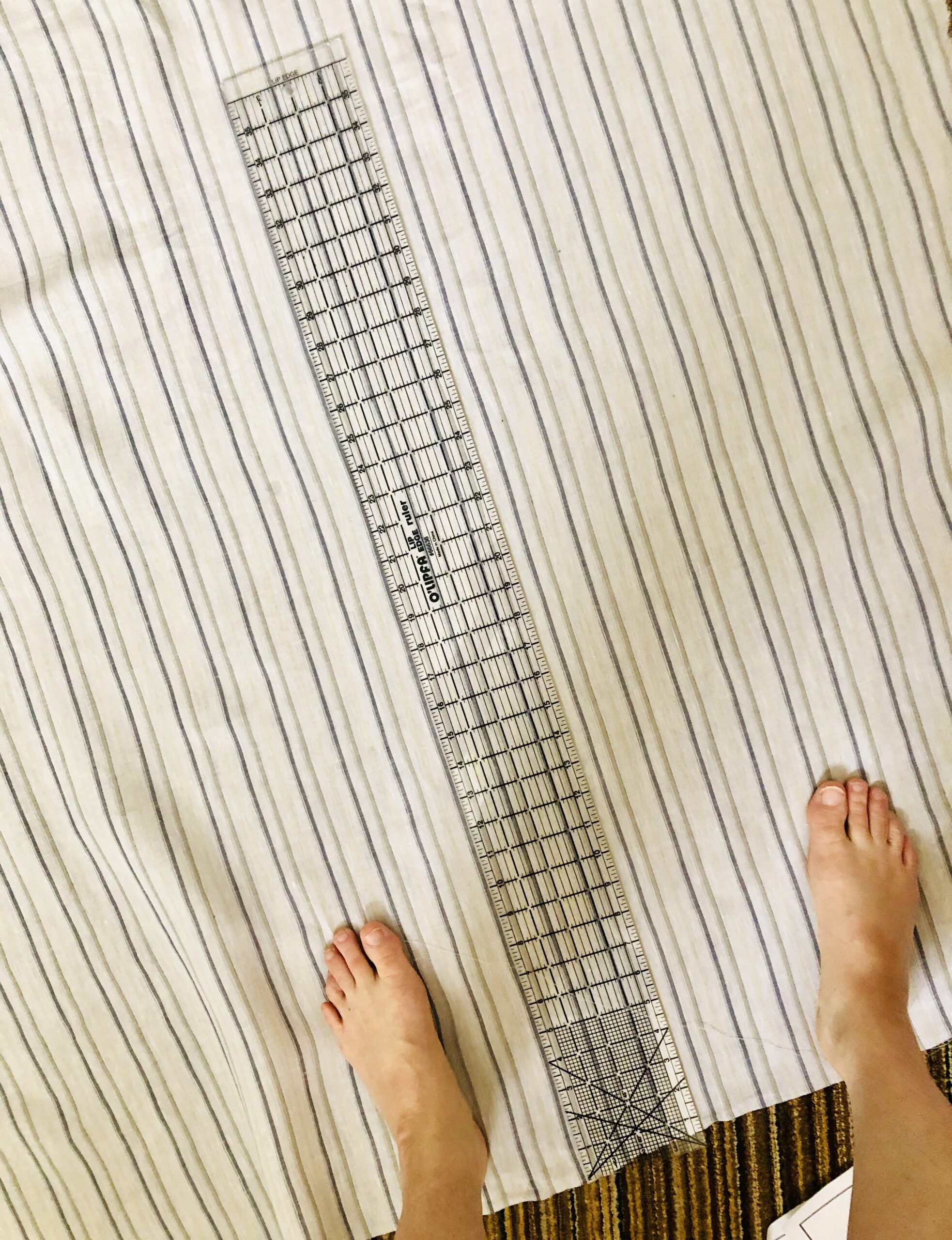 A quilting ruler lined up along the stripes of striped fabric