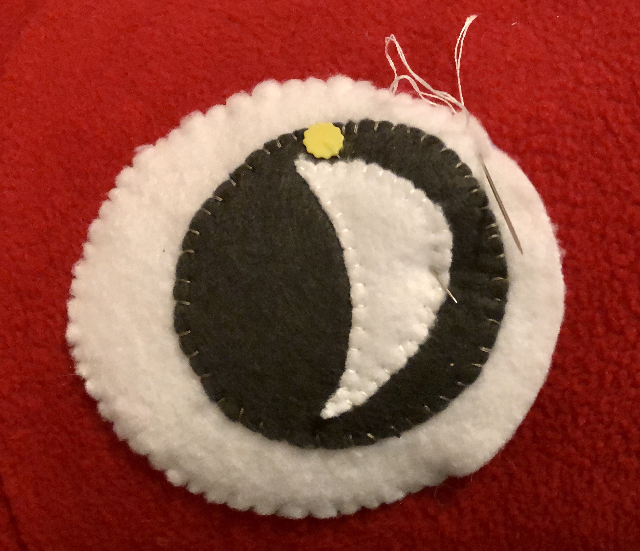 A white polarfleece eye is appliqued onto a red polarfleece filed.  The white eye has a dark grey iris and a white pupil