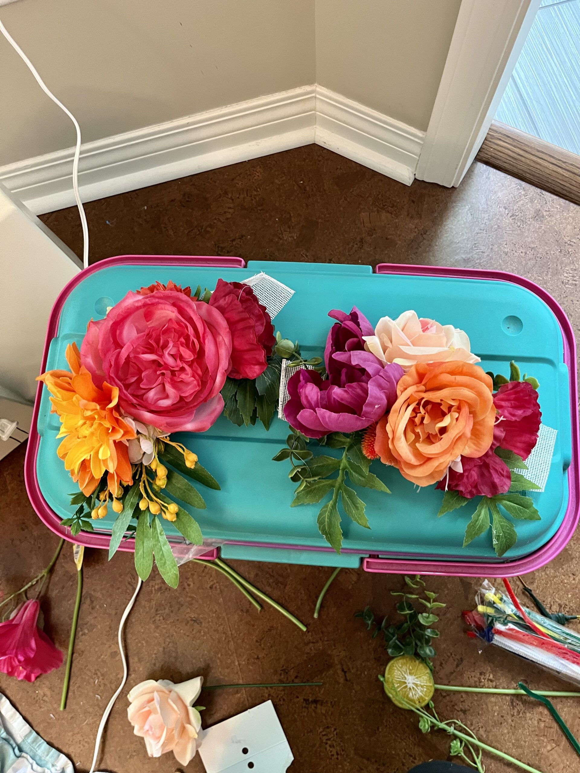 two bunches of flowers sit side by side on top of a blue plastic storage tub.