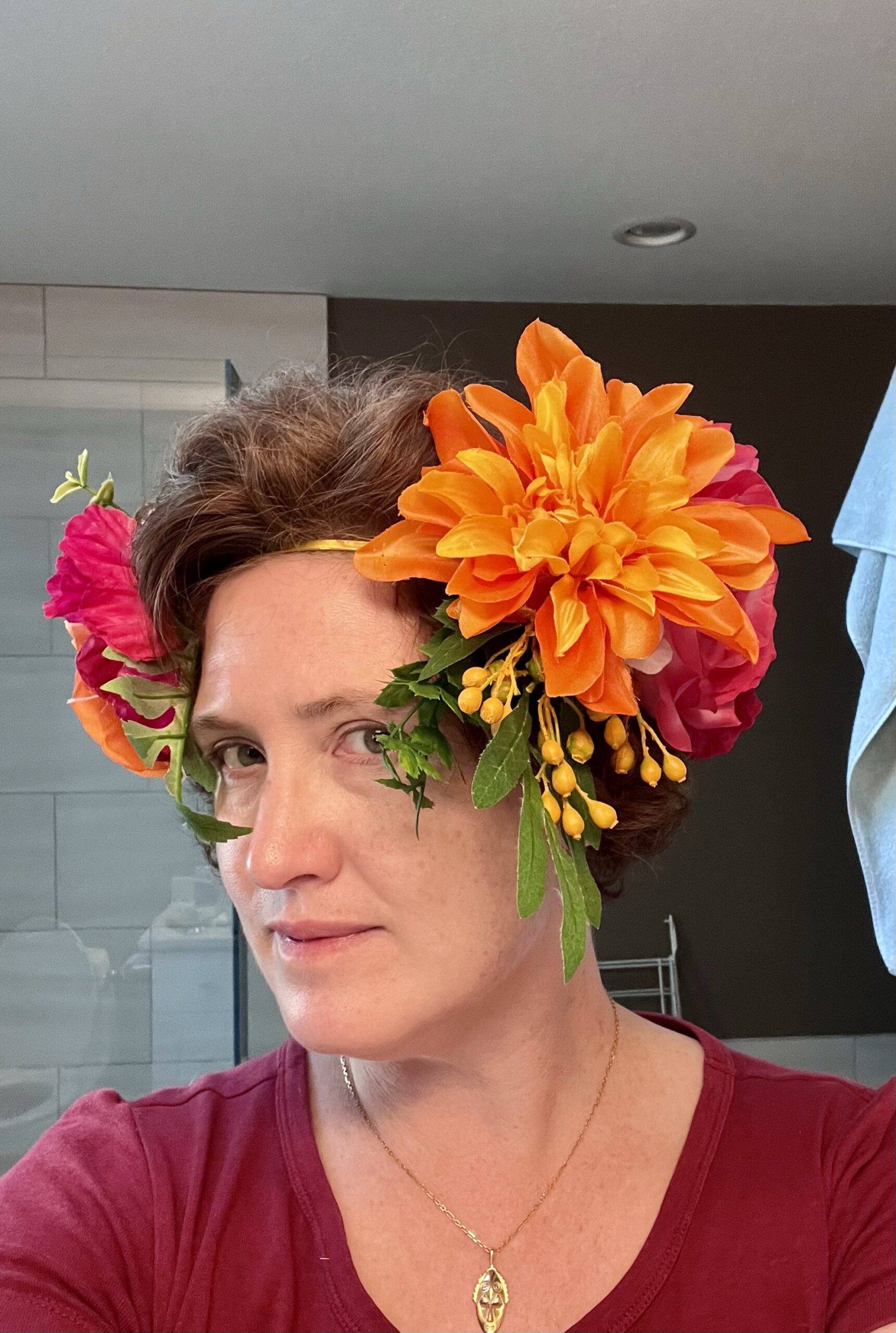 A woman is turned to present a 3/4 face to the camera. On her head is an alphonse mucha inspired headband heavy with flowers. - the angle of her head presents the flowers directly to the camera.