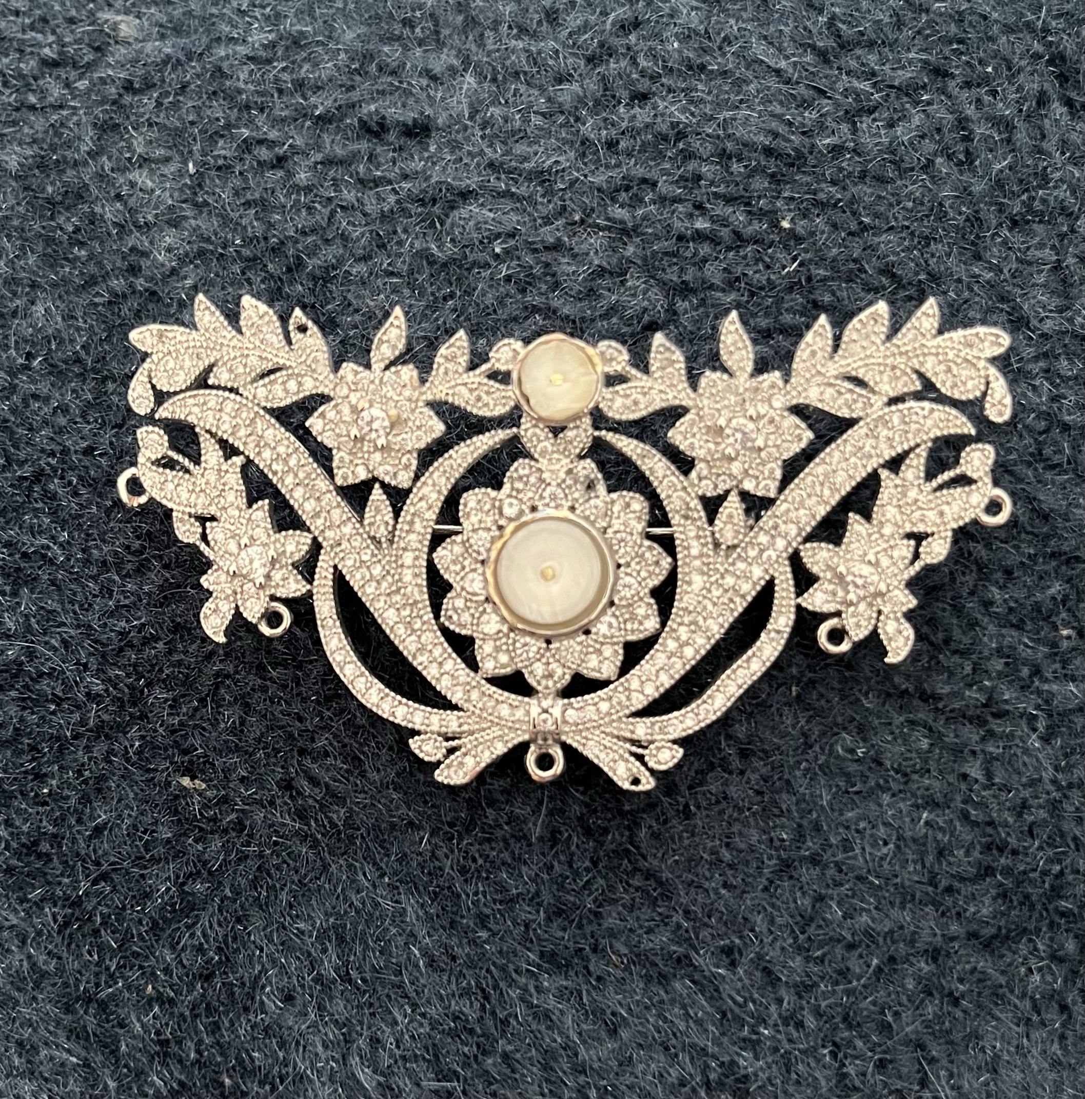 Pot metal brooch with central pearl elements ground off and dangle attachments removed